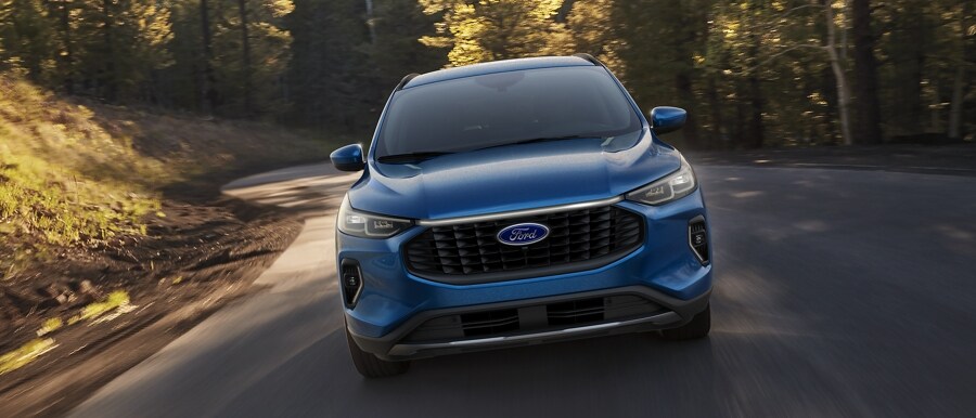 A 2023 Ford Escape® in Vapor Blue Metallic being driven around a curve in a forest