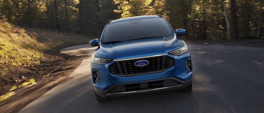 Una Ford Escape® 2023 en Vapor Blue Metallic circulando por una curva en un bosque