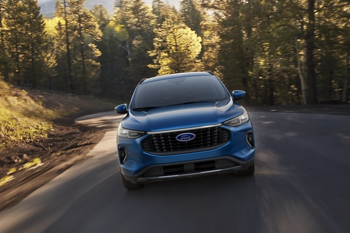Una Ford Escape® 2023 en Vapor Blue Metallic circulando por una curva en un bosque