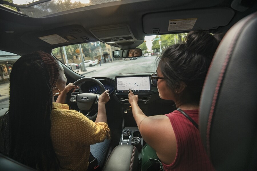 Interior de una Ford Escape® 2023 mientras un pasajero interactúa con la pantalla táctil