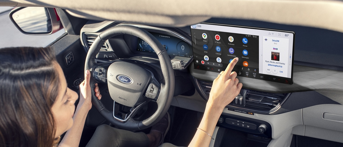 A woman seated in a 2024 Ford Escape interacting with icons on a dash-mounted touchscreen