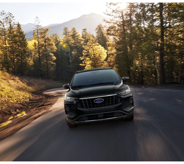 A 2024 Ford Escape seen from the front traveling down a country road