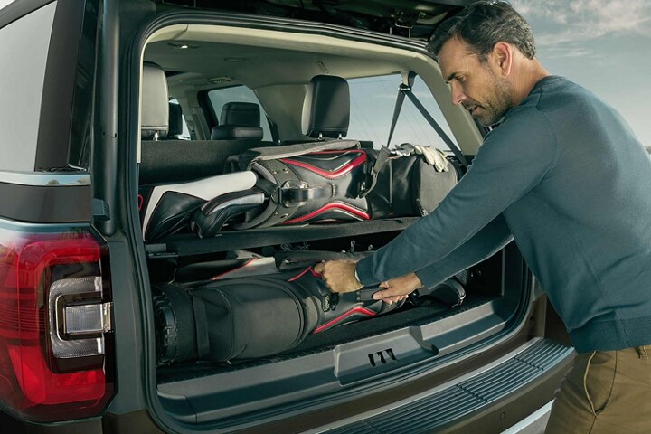 A man securing cargo in the back of a 2023 Ford Expedition SUV