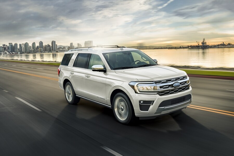 Una Ford Expedition 2023 circulando en una carretera cerca del agua con la ciudad al fondo