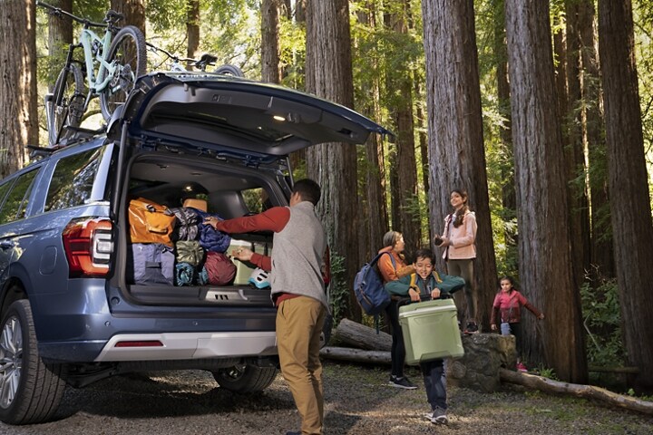 A family unloads cargo from a 2023 Ford Expedition SUV in the woods