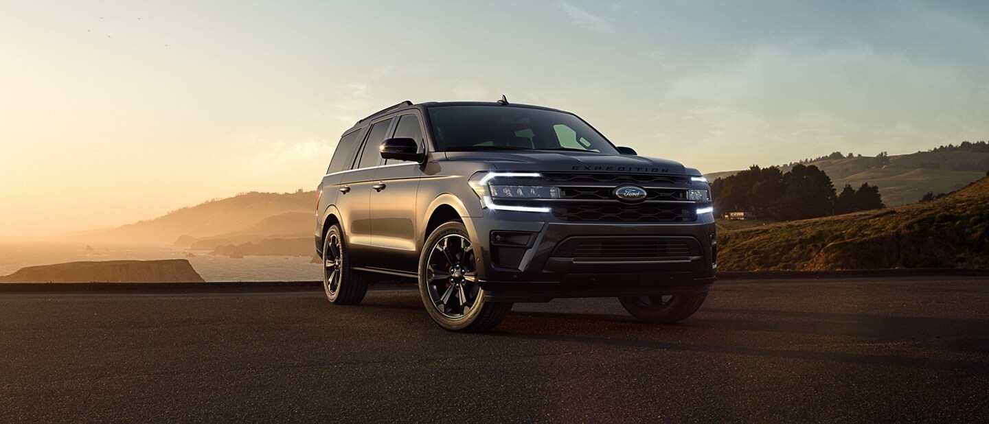 A 2023 Ford Expedition SUV parked next to a body of water at dusk