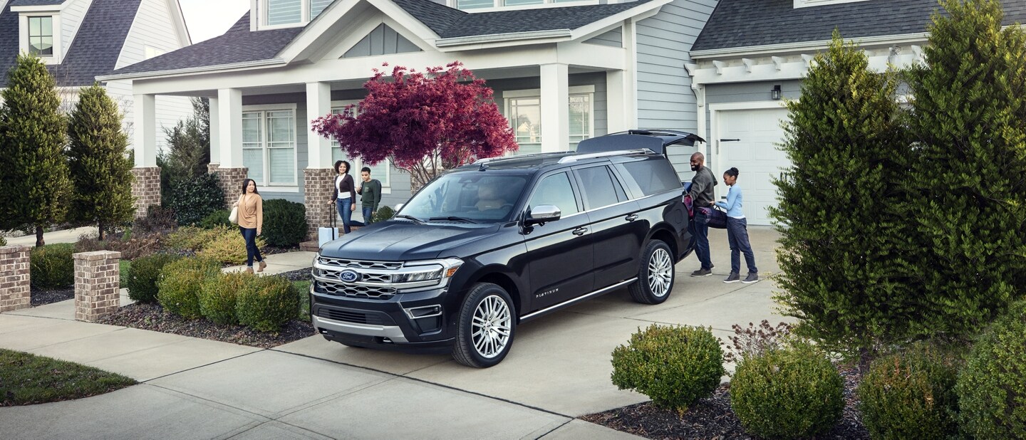 A family loading gear into a 2023 Ford Expedition parked at a house
