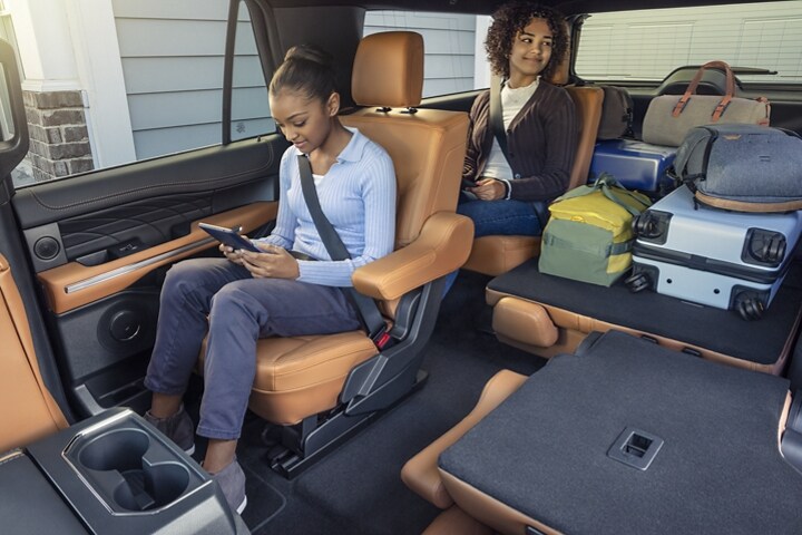 Una niña mirando su tablet en el asiento trasero de una SUV Ford Expedition 2023