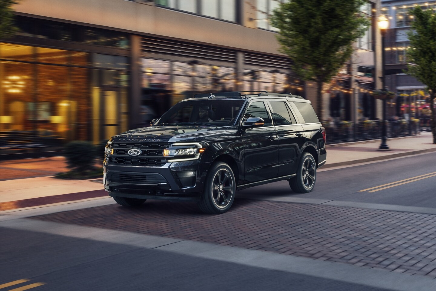 2023 Ford Expedition driving through a city street, highlighting its LED headlights