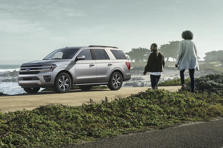 Two people approaching a 2023 Ford Expedition SUV parked next to a body of water
