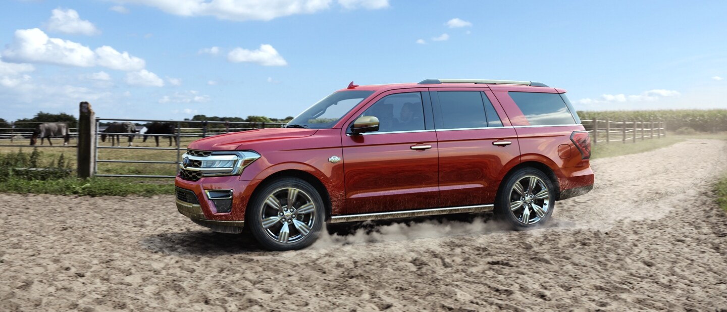 A 2023 Ford Expedition being driven down a dirt road at a farm