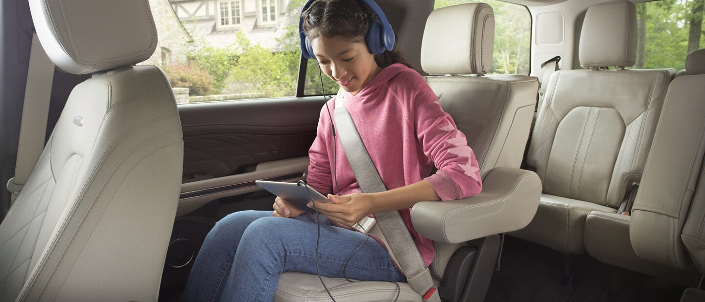 A girl inside a 2024 Ford Expedition SUV using her wireless tablet device connected with the in-vehicle Wi-Fi Hotspot
