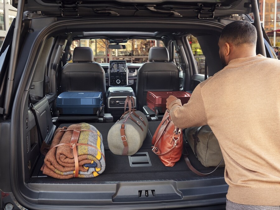 A man loading bags and other items into the cargo trunk space of a 2024 Ford Expedition
