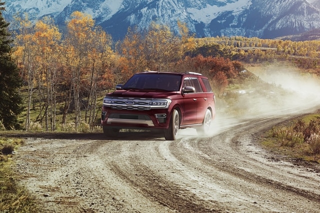 A 2024 Ford Expedition being driven on a dirt road with mountains behind it