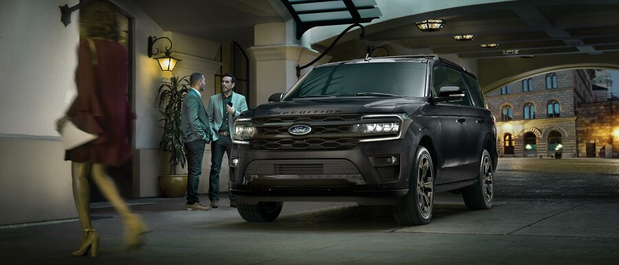 Two men standing next to a 2024 Ford Expedition LTD outside an upscale hotel