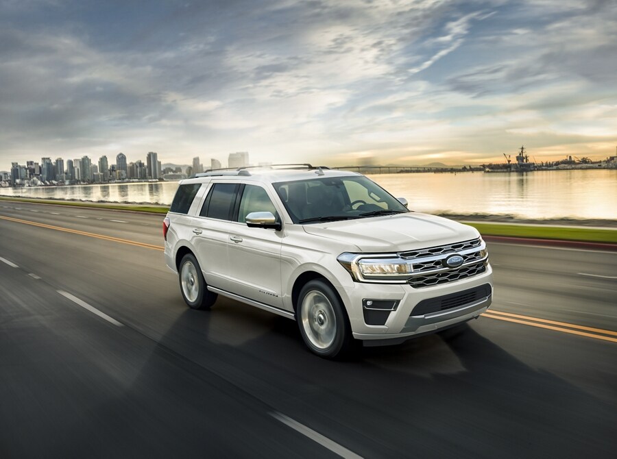 A 2024 Ford Expedition being driven on a highway near water with the city in the background