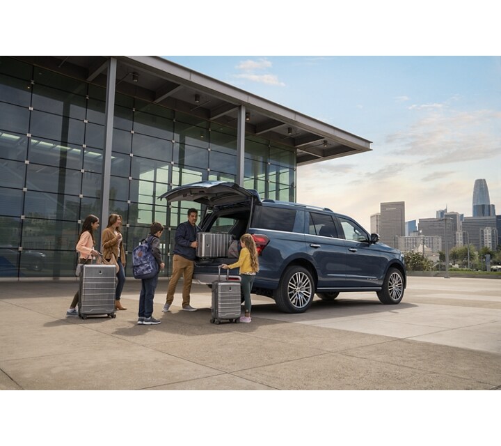 A 2024 Ford Expedition with its cargo space being loaded up with bags and luggage by a family at the airport