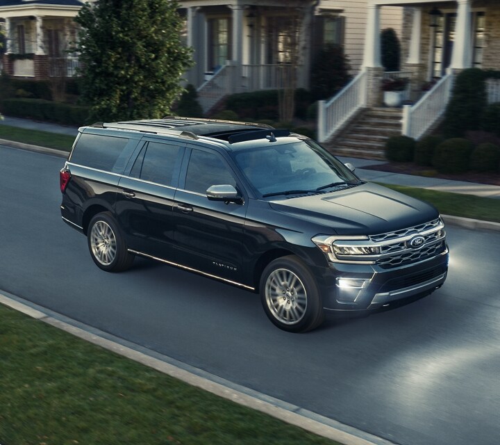 A 2024 Ford Expedition® driving down a residential street with its LED fog lamps on