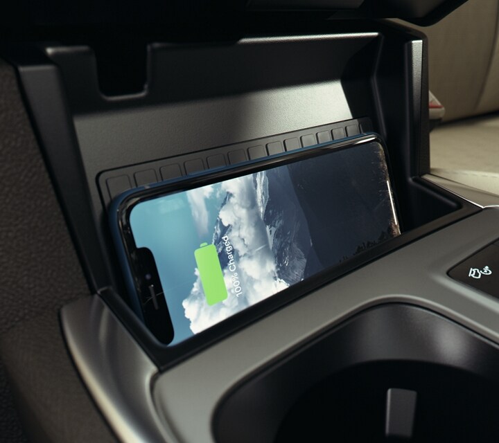 Primer plano del interior de una SUV Ford Explorer® 2023 y un smartphone colocado de costado en la base de carga inalámbrica