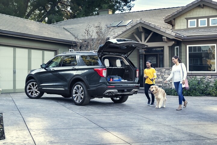 El modelo Ford Explorer® Platinum 2023 con una familia con un perro que camina hacia la zona de carga