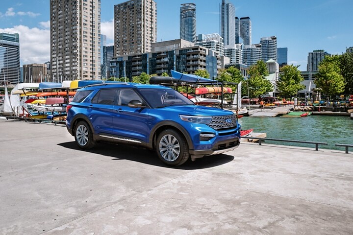 El modelo Ford Explorer® Limited 2023 en Atlas Blue Metallic estacionado junto a un soporte de kayaks junto a un río