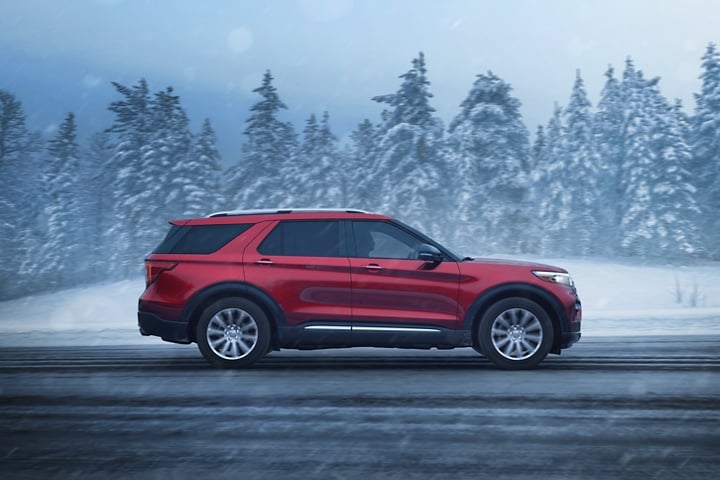 2023 Ford Explorer® Limited model in Rapid Red being driven down a road with a snowy background