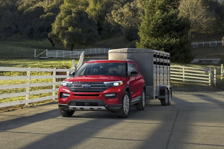 El modelo Ford Explorer® King Ranch® 2023 estacionado cerca de un establo con un remolque para caballos enganchado