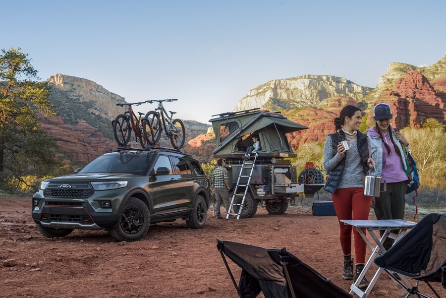 2023 Ford Explorer® Timberline® SUV in Forged Green Metallic parked in the desert with a trailer-top tent and family