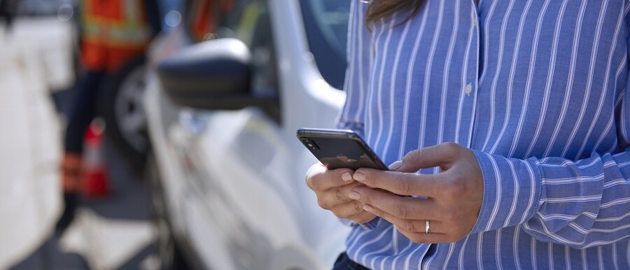Person uses a smartphone while a technician repairs a tire on their vehicle