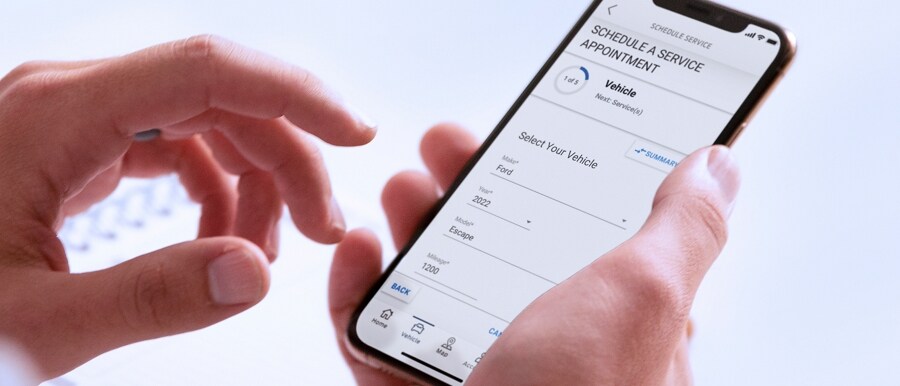 A hand holds a smartphone displaying the FordPass® App