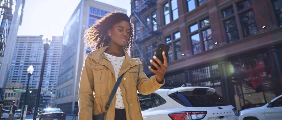 Person walking on a city sidewalk using their smartphone