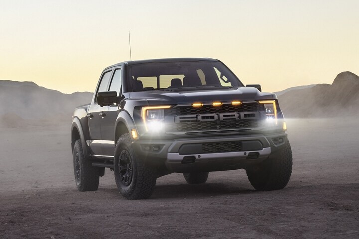 A 2023 Ford F-150® Raptor® parked in the desert with headlamps on