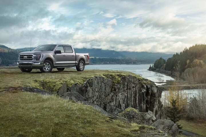 A 2023 Ford F-150® on a grassy cliff near a lake