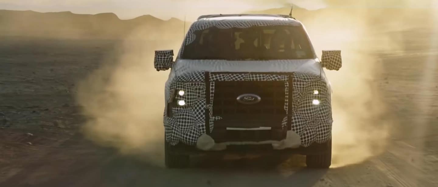 Vista delantera de una Ford F-150® Powerboost Hybrid 2023 camuflada andando todo terreno en el desierto