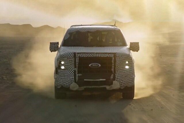 Front view of a disguised 2023 Ford F-150® Powerboost Hybrid being driven off road in the desert