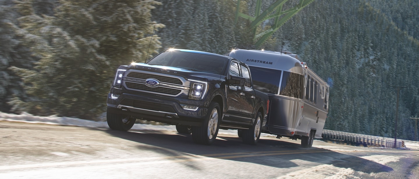 A 2023 Ford F-150® towing a camper up an inclined road