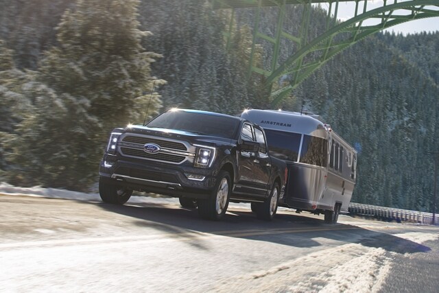 A 2023 Ford F-150® towing a camper up an inclined road