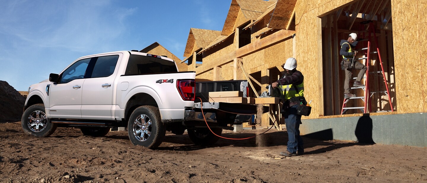 Un hombre cortando madera en la puerta trasera de una Ford F-150® 2023