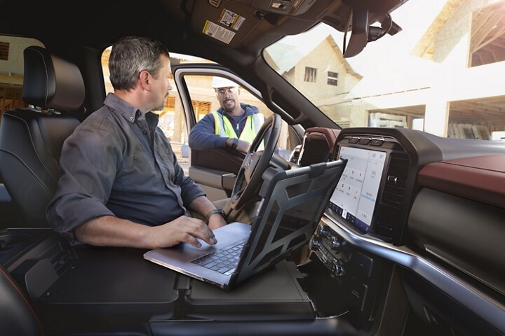 A person inside a parked 2023 Ford F-150® on their laptop