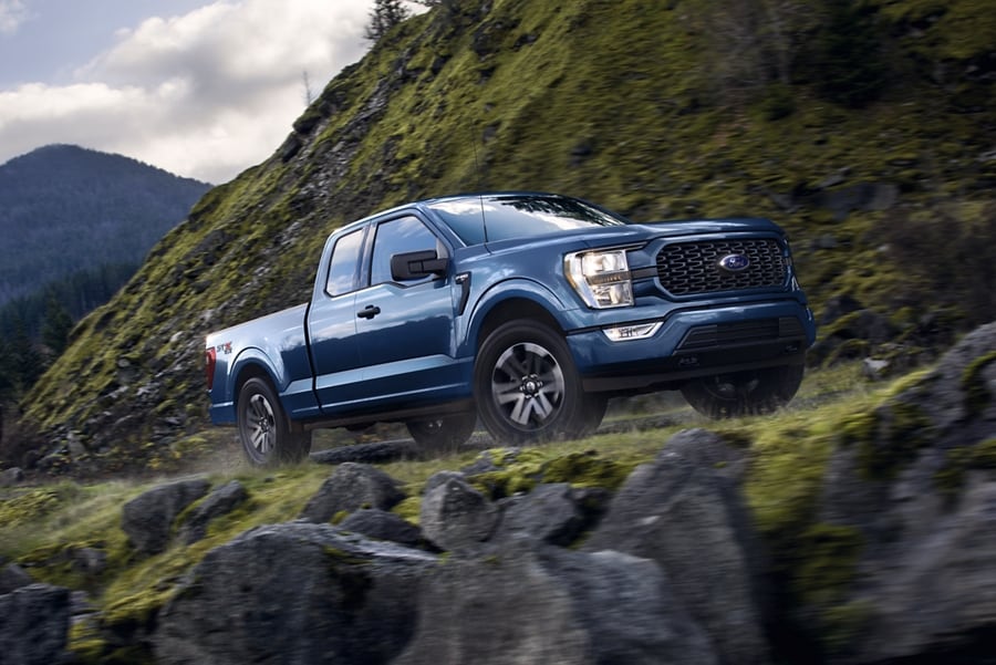 A 2023 Ford F-150® XLT in Atlas Blue being driven on a mountain road