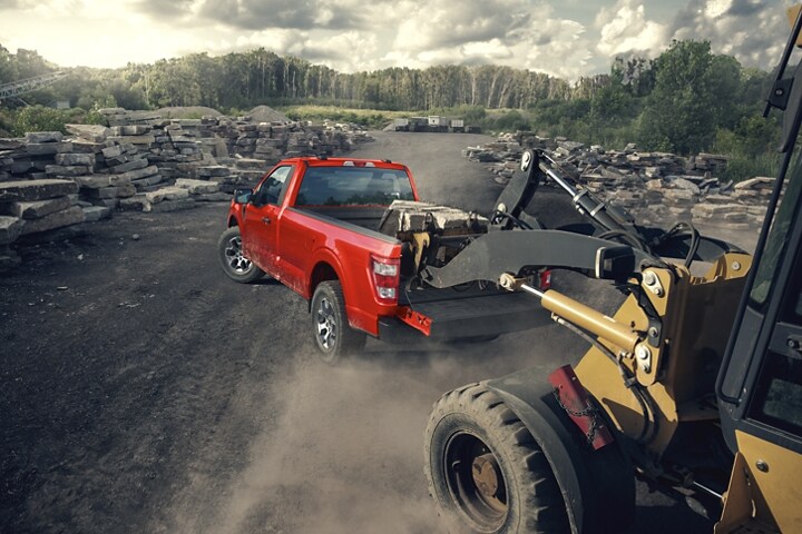 Two people loading an industrial fan into the bed of a 2023 Ford F-150®