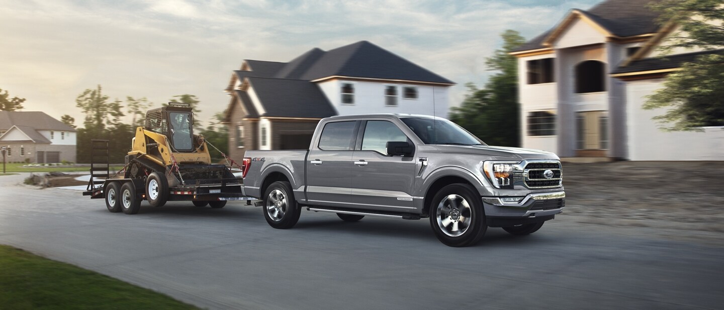Una Ford F-150® 2023 remolcando una retroexcavadora en un tráiler