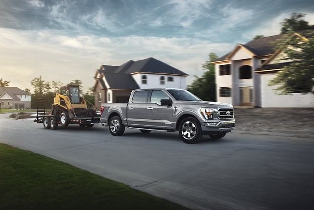 A 2023 Ford F-150® towing a backhoe on a trailer