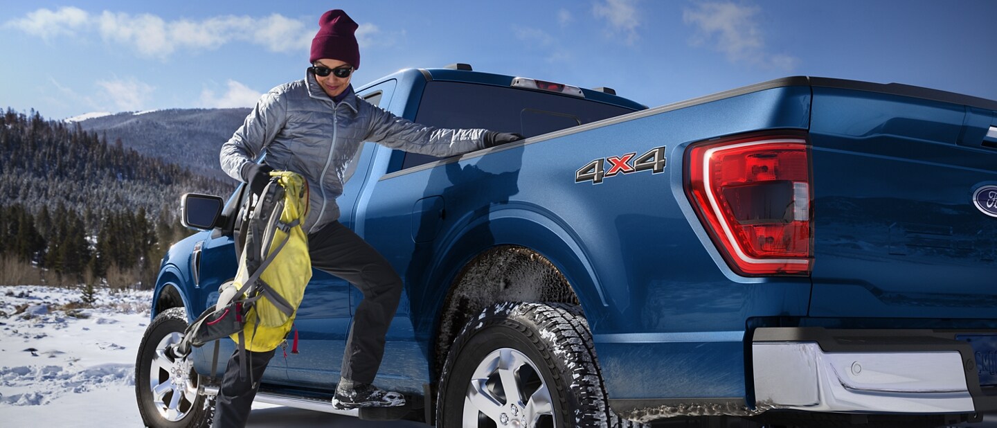 Image of a man using the side step to put gear into the bed of the truck