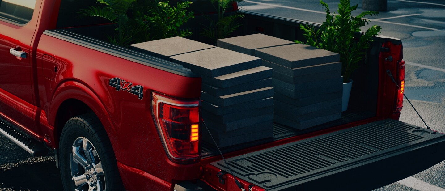 Primer plano de una Ford F-150® 2023 con la puerta trasera levadiza baja y bloques para pavimento en la plataforma