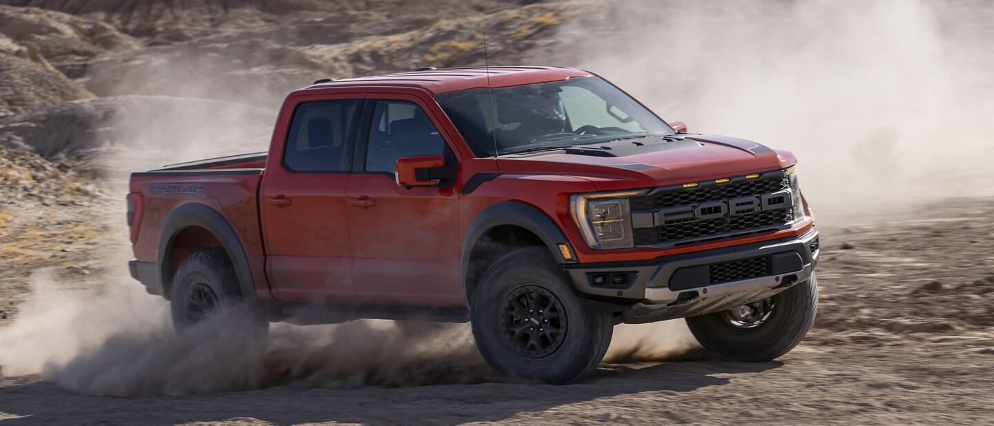 A 2023 Ford F-150® Raptor® being driven in the desert kicking up dust