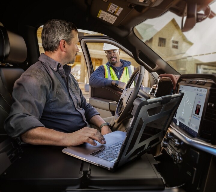 Man using a laptop on the interior work surface while talking with a co-worker