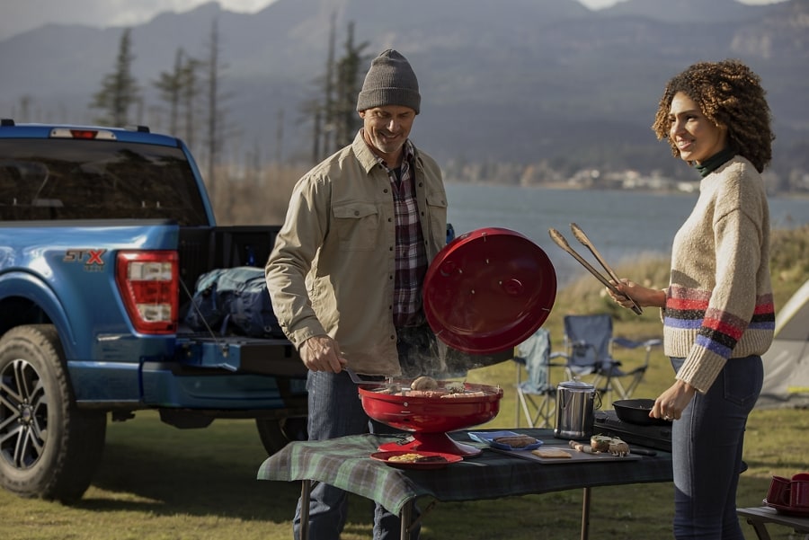 Man and woman grilling near a 2023 Ford F-150® pickup
