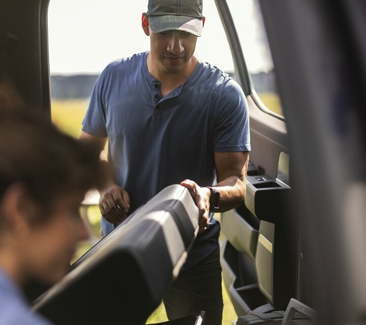 Man lifting the rear fold-up seat to retrieve items from the storage area