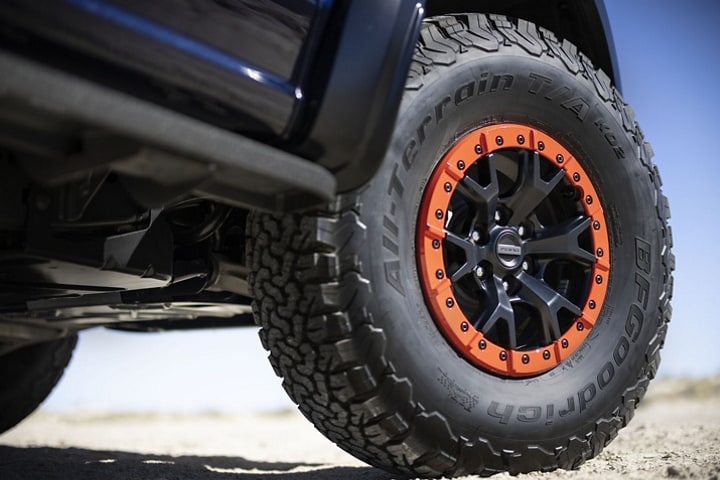 Close-up of the Code Orange accented bead-lock wheels and 37-inch tires on the 2023 Ford F-150® Raptor R™